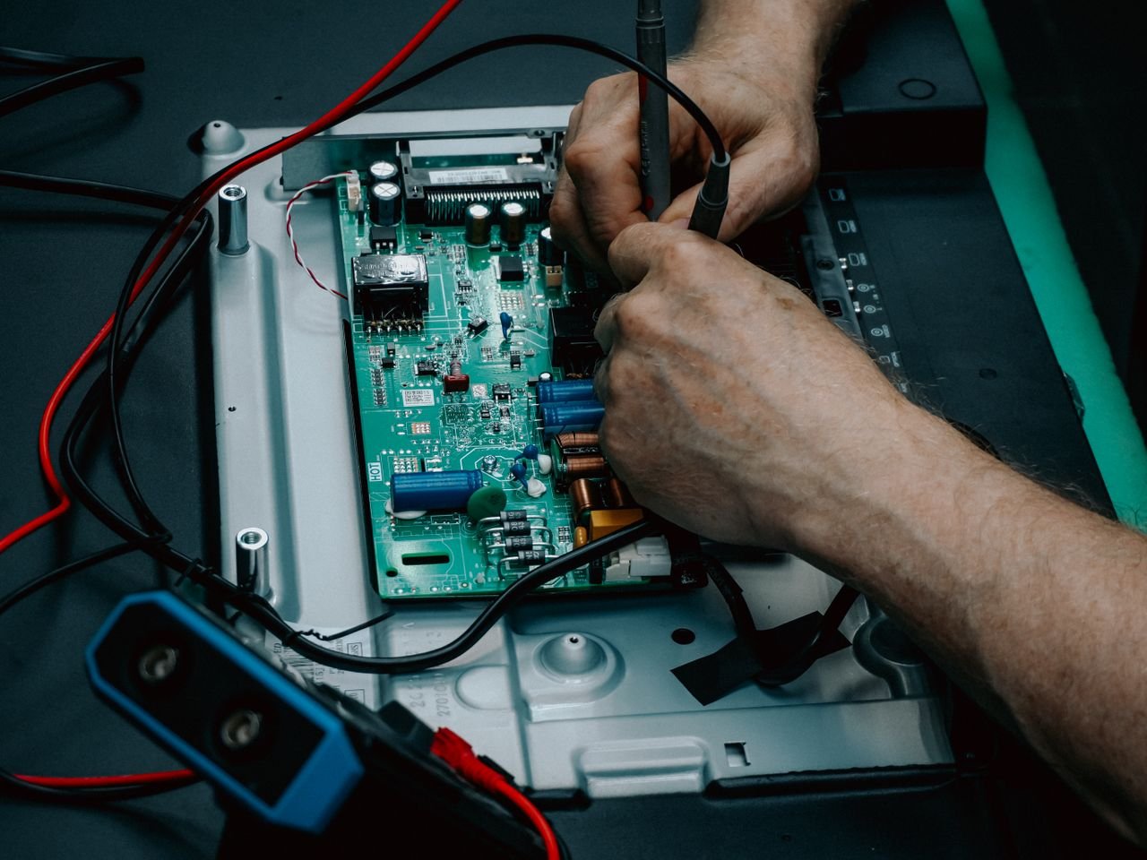 Close-up of hands repairing electronic circuit board, showcasing detailed technology work.