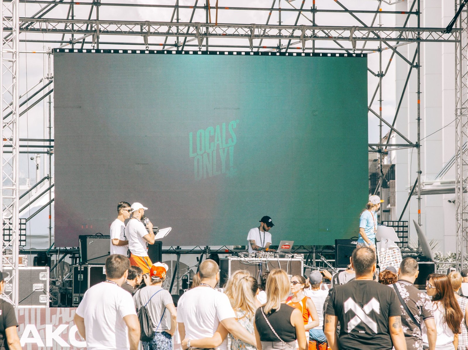 Lively outdoor concert featuring a DJ and performers with audience engagement.
