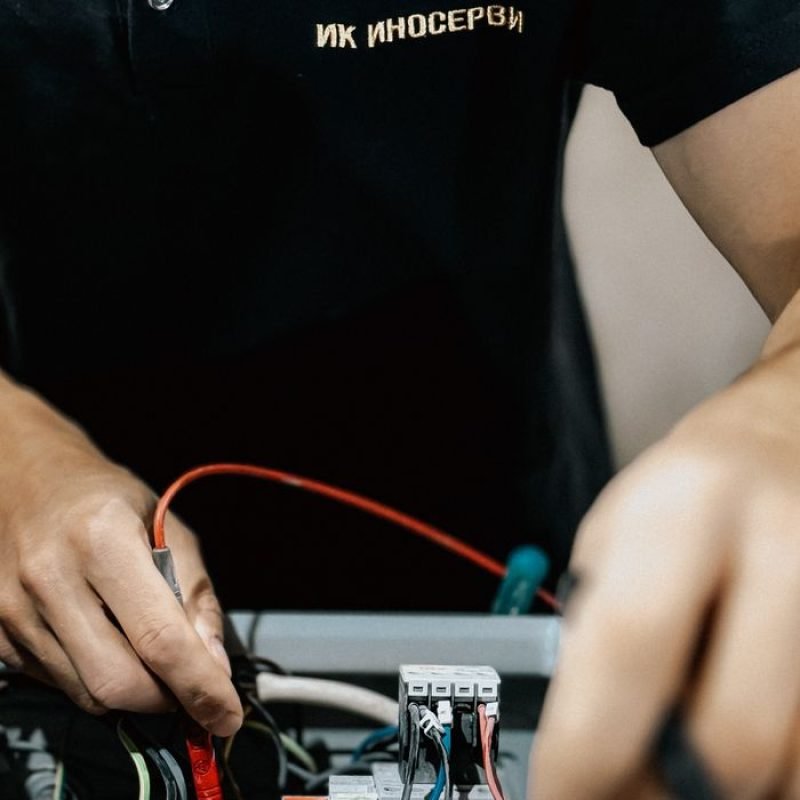 Electrical technician repairing a circuit board with precision tools indoors.